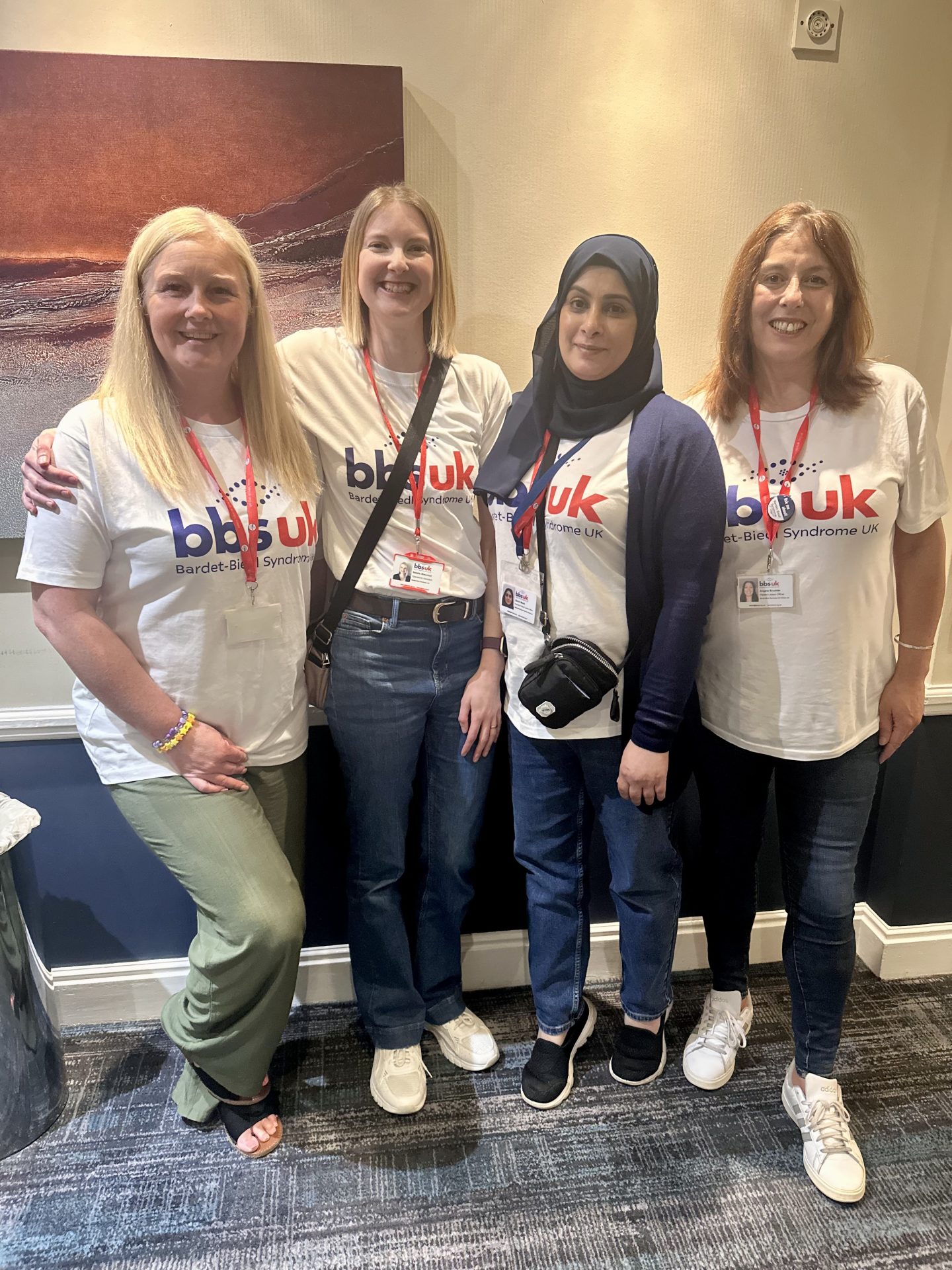 Four women are stood side by side smiling at the camera. They are wearing white BBS UK t-shirts.