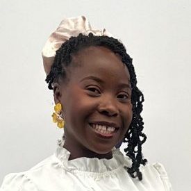 A woman is looking at the camera and smiling. She is wearing a white top.