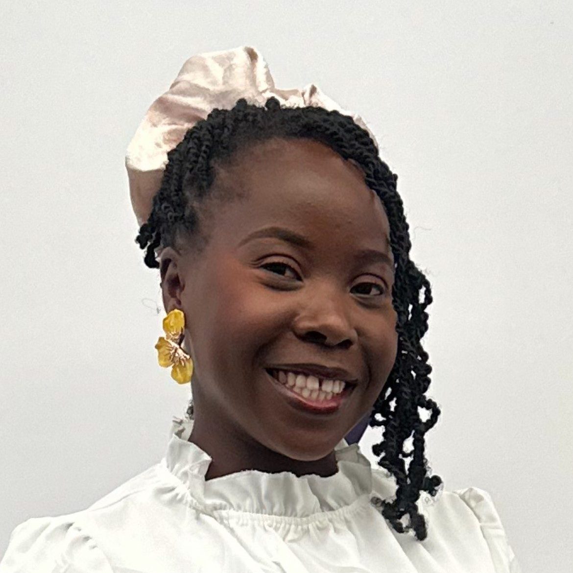 A woman is looking at the camera and smiling. She is wearing a white top.