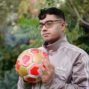 A young man is holding a football in his hand and looking to the side.