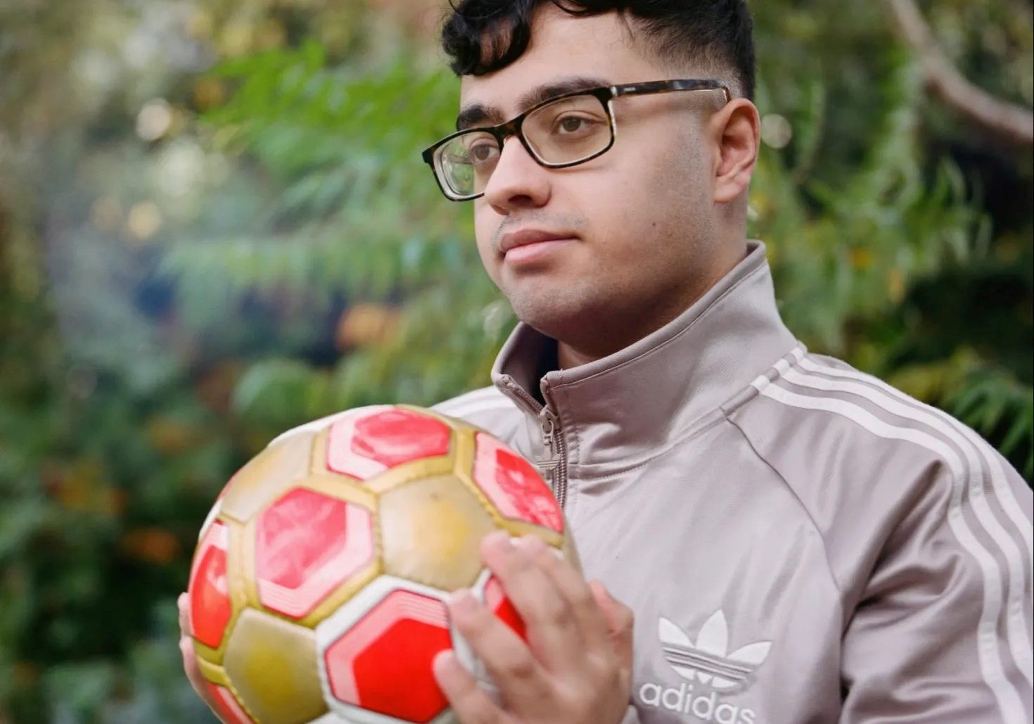 A young man is holding a football in his hand and looking to the side.