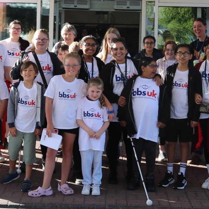 A large group of smiling children and adults wearing white BBS UK t-shirts.