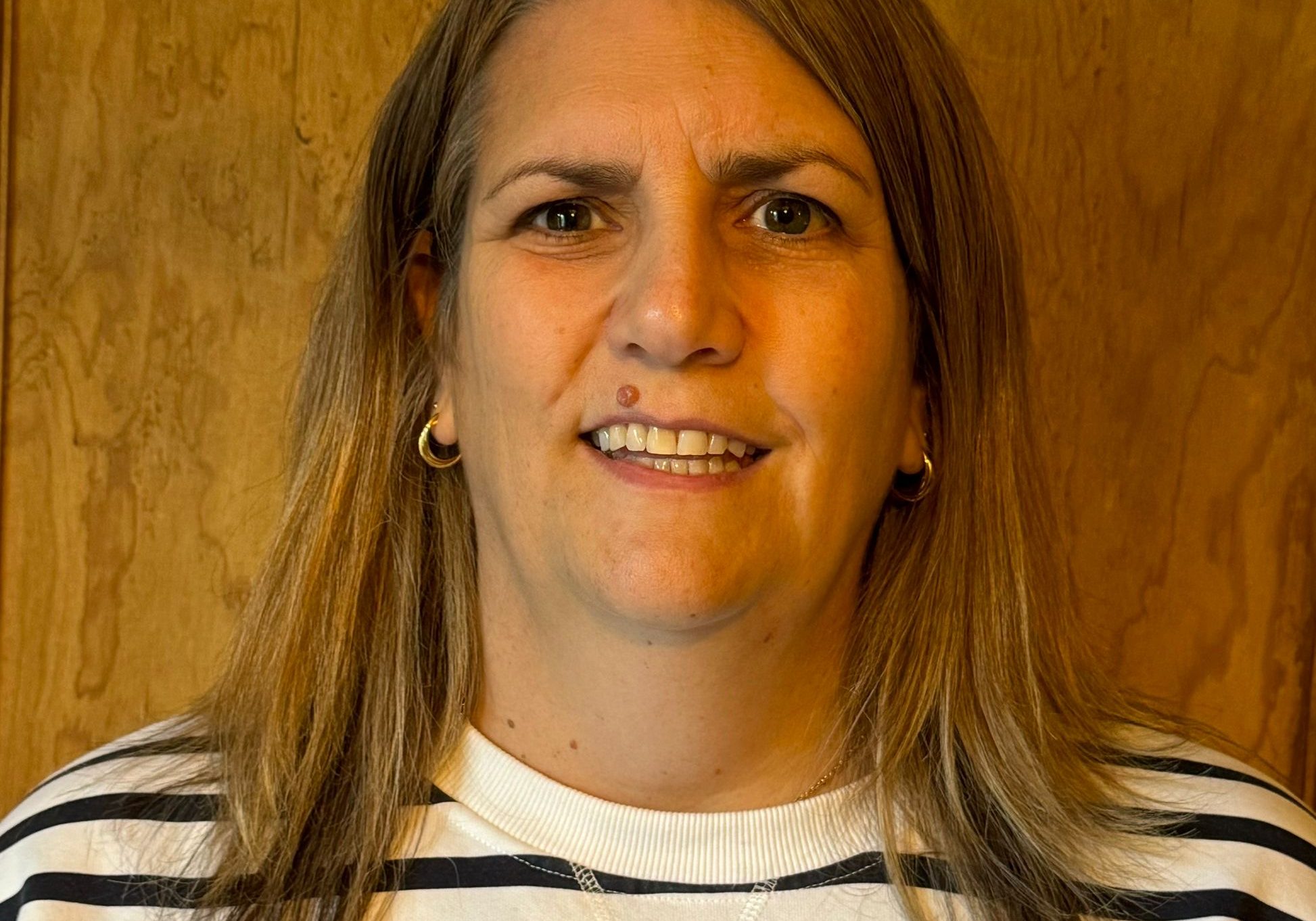 Woman looking at the camera wearing a white and black striped top.