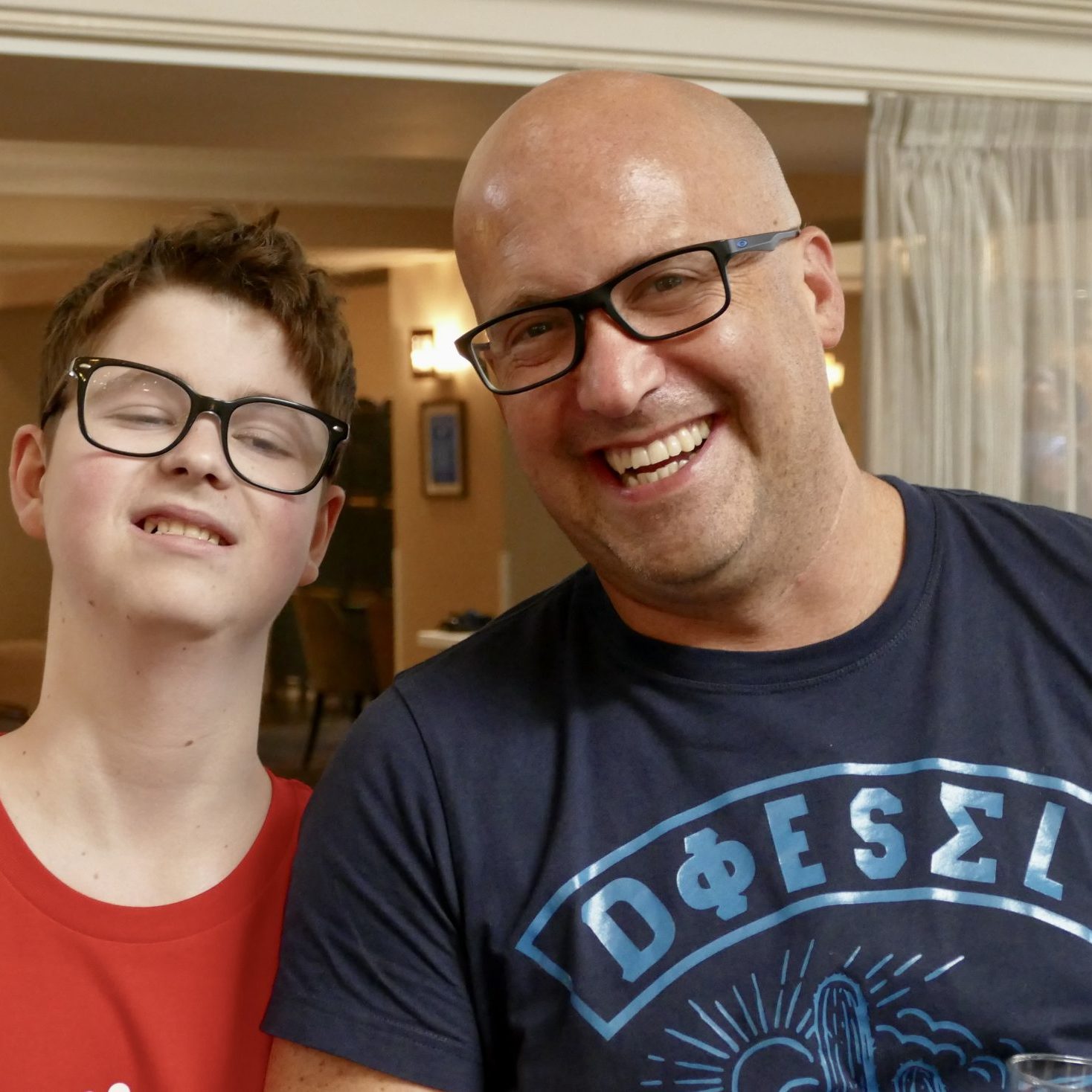 A man and a teenage boy are stood next to each other and similing.