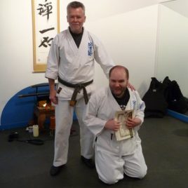 Two men are wearing white martial arts robes.