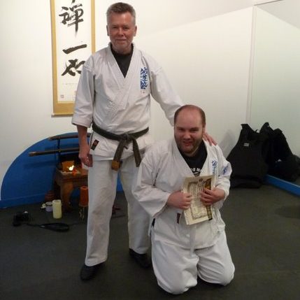 Two men are wearing white martial arts robes.